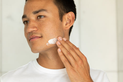 A man applying moisturizer to their face