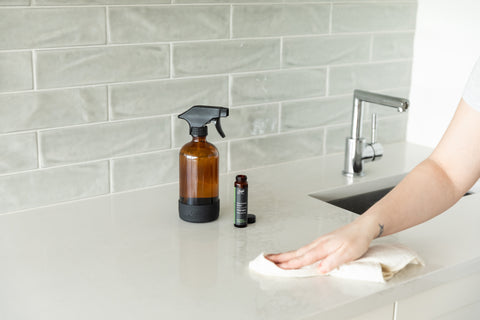 A person using Saje multi-surface cleaner to wipe down their kitchen counter
