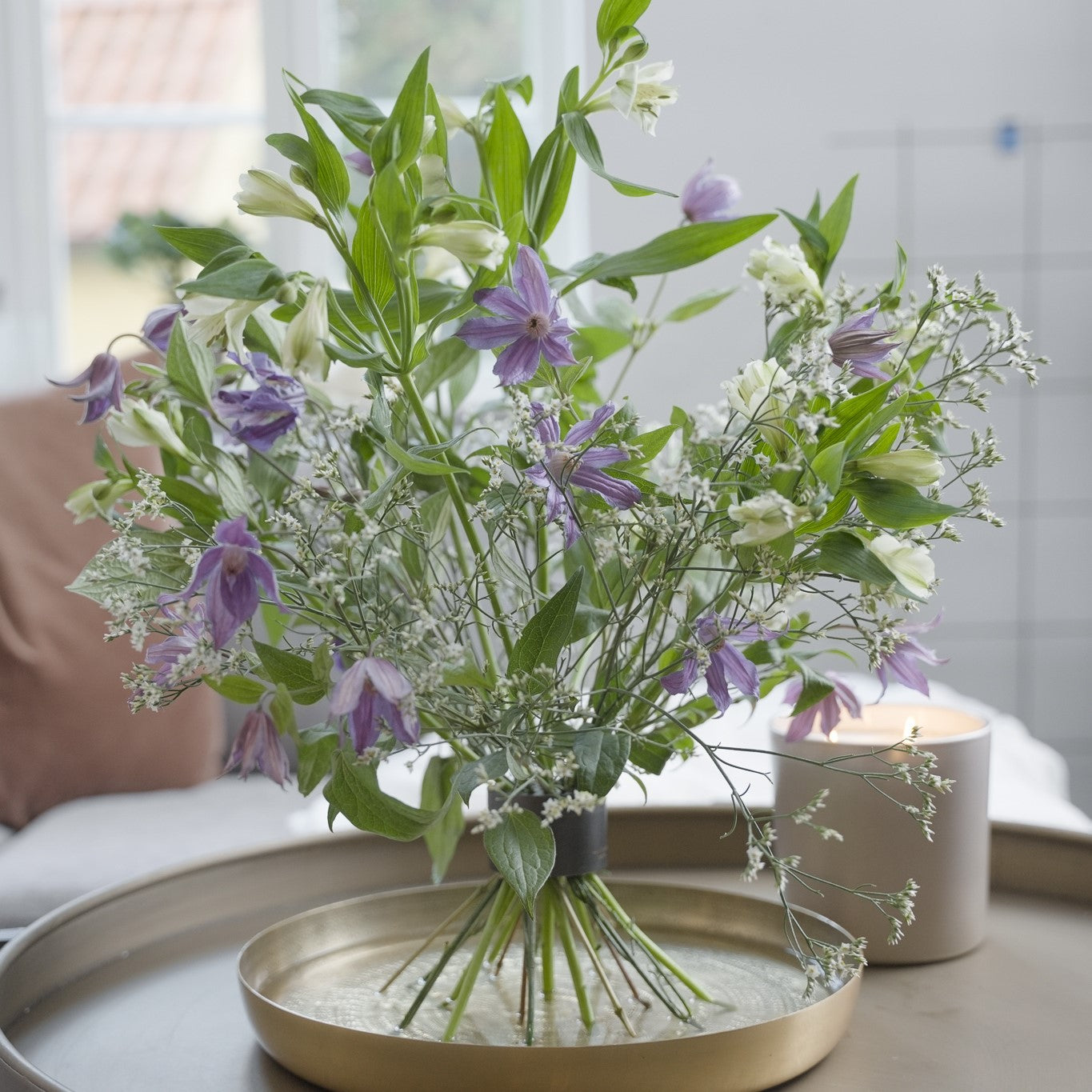 Un bouquet di fiori viola e bianchi, tra cui campanule e alstroemeria, allestito con un Hanataba Bouquet Twister in Pitch Black.