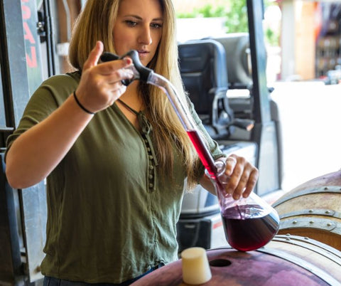 Woman at brewery or distillery sampling from barrels