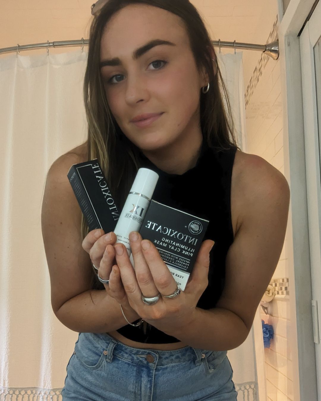 Brunette holding Intoxicate skincare products