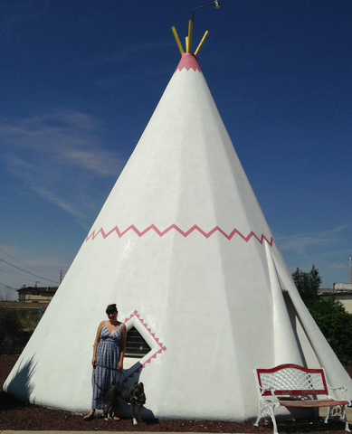 A woman and her grey pit bull dog standing in front of a concrete teepee