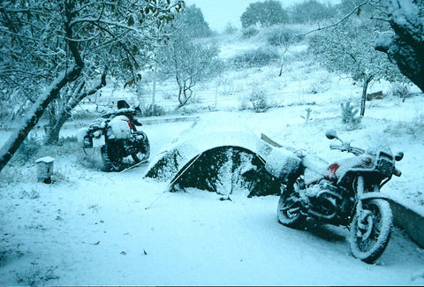2 motorbikes and a tent covered in snow