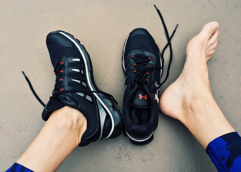 Black pair of running shoes, one on and one off, showing bare foot