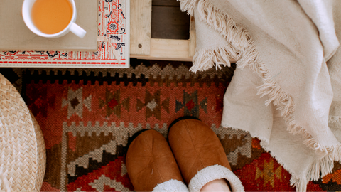 an image of slippers next to a blanket and a cup of tea