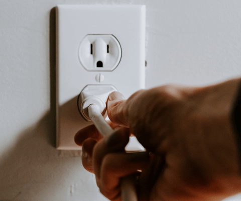 Close-up of a cord going into a power outlet