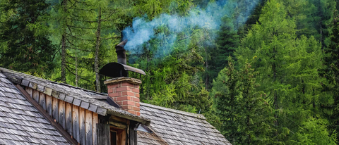 an image of a brick chimney on top of a cottage in the forest