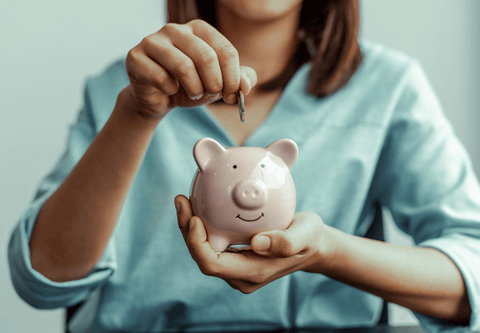 Woman placing a coin inside a piggy bank