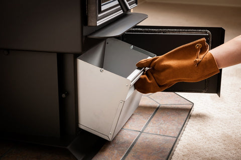 A gloved hand accesses a pellet stove drawer