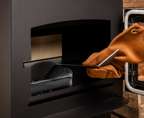 A gloved hand accessing a pellet stove