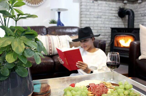 A photo of a woman reading near a Forge & Flame pellet stove