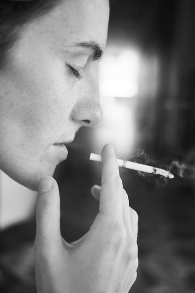 Woman closing her eyes holding cigarette