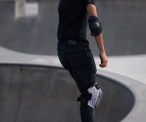 Man at skate park wearing elbow pads and knee pads