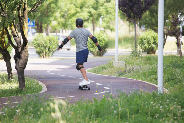 A skater wearing skate pads riding down a street
