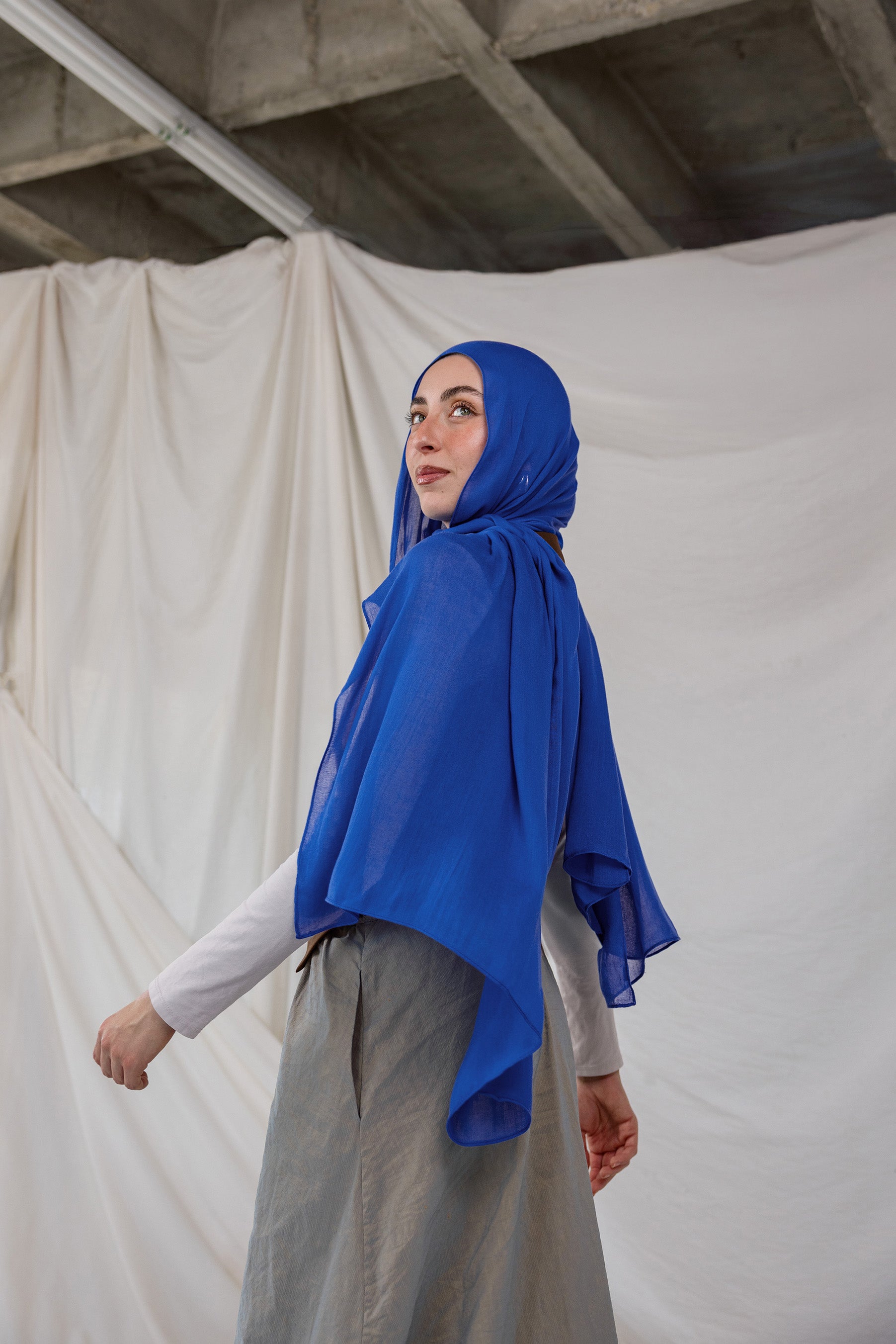 Spirulina Blue scarf pictured on model, this scarf by VELA is bright electric blue.