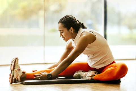 Frau dehnt ihr Bein auf Yogamatte