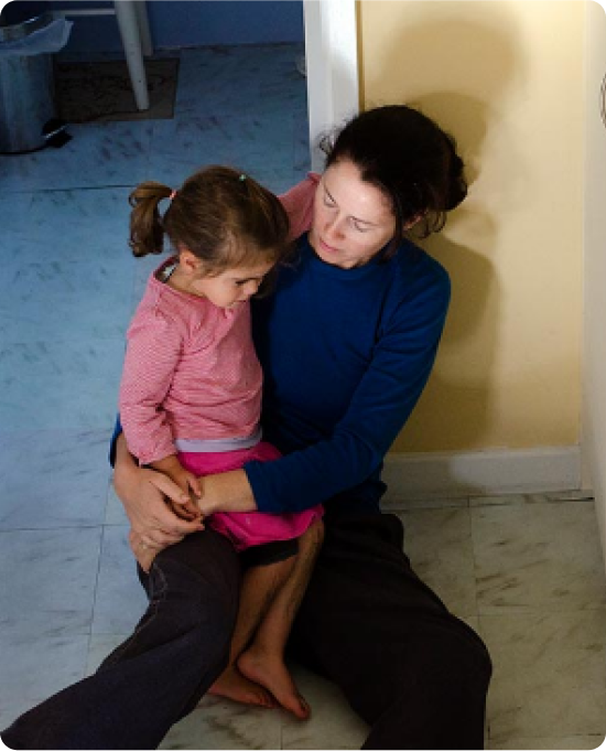 A woman sitting on the floor holding a young girl in her lap.