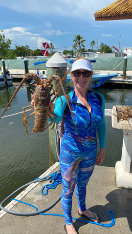 Woman holding a large spiny lobster.