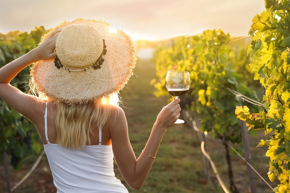 young woman with glass of wine in vineyard