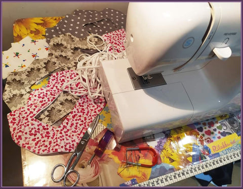 A white sewing machine on a colorful table with patterned fabric scraps around it.