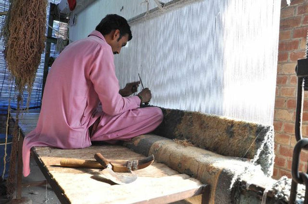 A skilled rug weaver knotting on a vertical loom