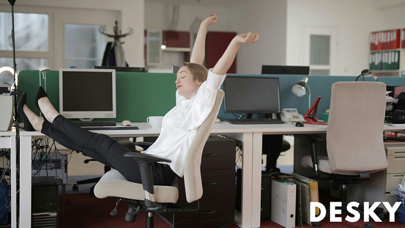 Woman sitting in front of desk stretching sitting on computer chair