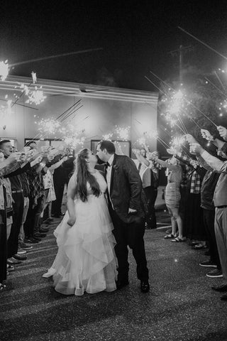 Bride and Groom at wedding exit with guests holding long wedding sparklers