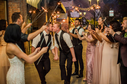 gay guys getting married kissing under sparklers at wedding sendoff