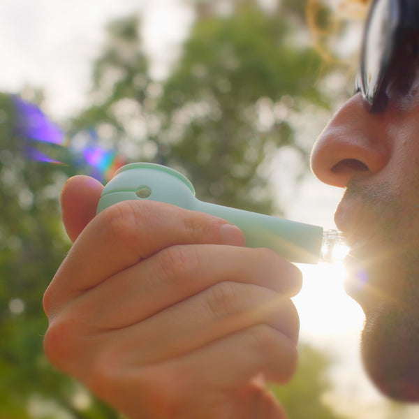 A guy with sunglasses smoking with his Weeday spoon pipe on a sunny day.