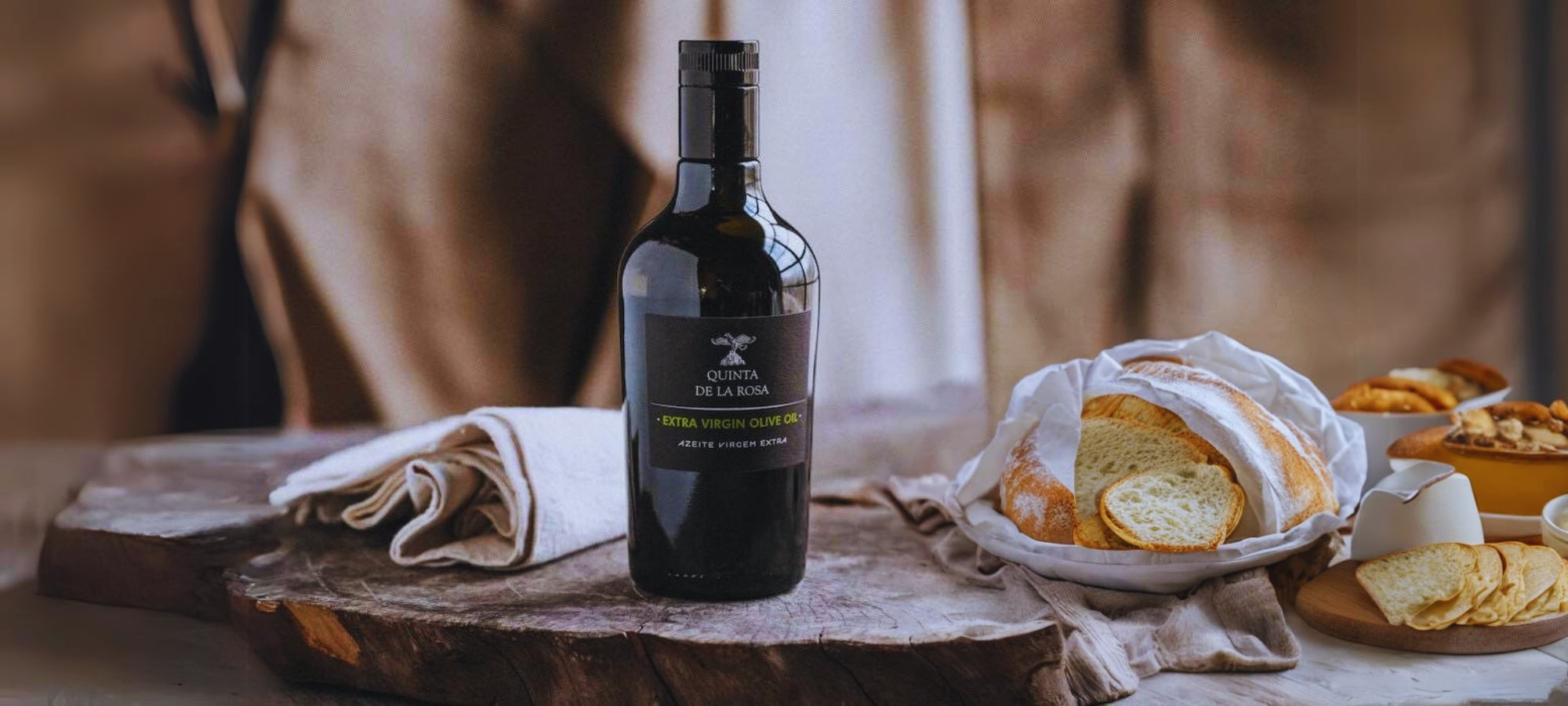 Olivenöl von Quinta de la Rosa, daneben ein Brotkorb auf einer Holzscheibe.