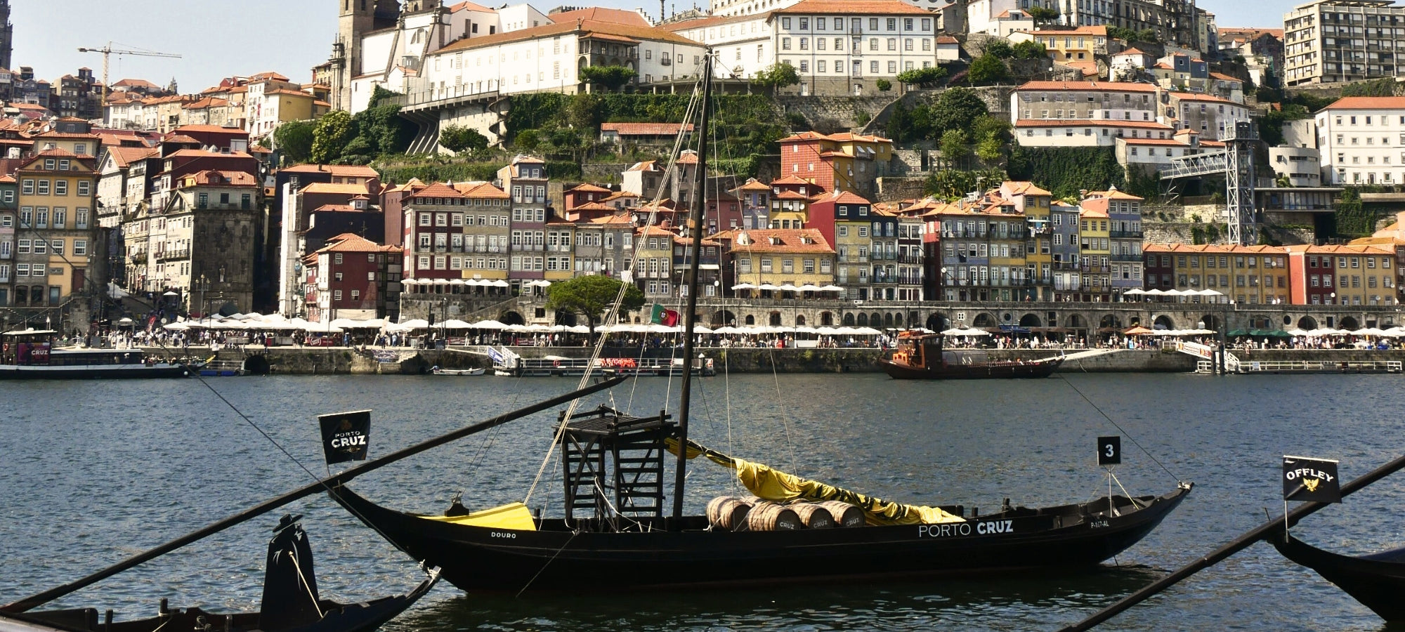 Beschreibung des Bildes: Der majestätische Douro-Fluss fließt durch eine atemberaubende Landschaft. Auf dem ruhigen Wasser sind alte Barken zu sehen, beladen mit traditionellen Portweinfässern. Die Sonne taucht die Szene in warmes Licht und lässt die Spiegelung der Boote auf dem Fluss glänzen. Ein malerischer Anblick, der die zeitlose Schönheit und die reiche Weintradition des Douro-Tals widerspiegelt.
