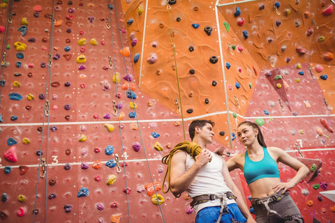 Two climbers on date at the climbing gym talking it up between climbs