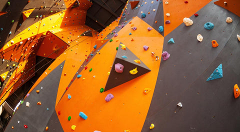 Looking up at tall walls in a climbing gym covered with many routes