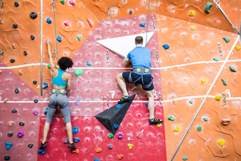 Two climbers on a date sport climbing next to each other on adjacent routes in the gym