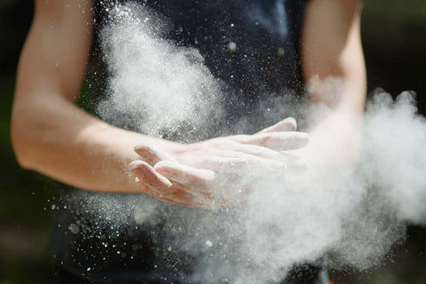 Climber clapping hands together after chalking up to create a small cloud of chalk dust
