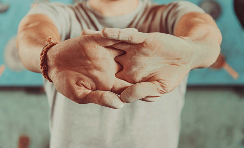 Climber stretching forearms by interlacing fingers and pushing palms out.