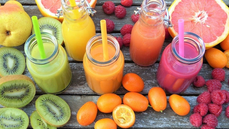 fünf verschiedene Fruchtsmoothies mit ihren jeweiligen Früchten