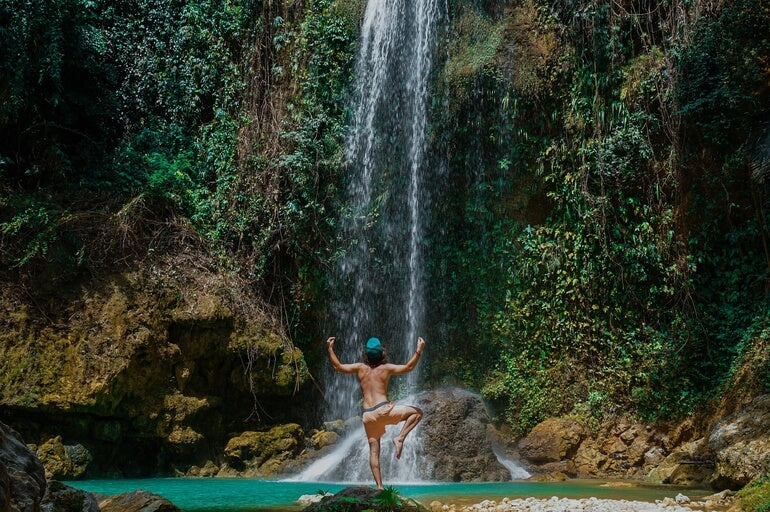 El hombre se para frente a una cascada