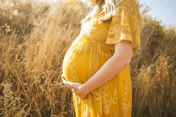 Eine schwangere Frau im gelben Kleid