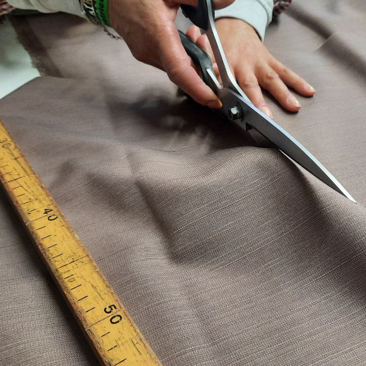Le mani di un artigiano tagliano un pezzo di stoffa