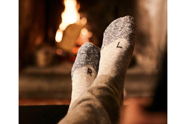 photo of person's feet up by the fire, wearing fashionable warm winter socks with L and R embroidered on the left and right sock