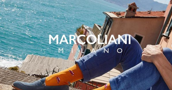 Image of person's legs bent up towards chest, Marcoliani socks on feet, beautiful Italian background