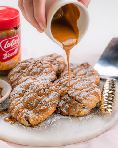 Pouring Lotus Biscoff Spread over freshly baked Biscoff Swirls