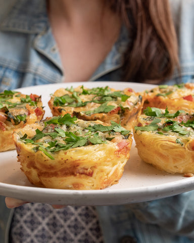 lady holding plate of carbonara quiches