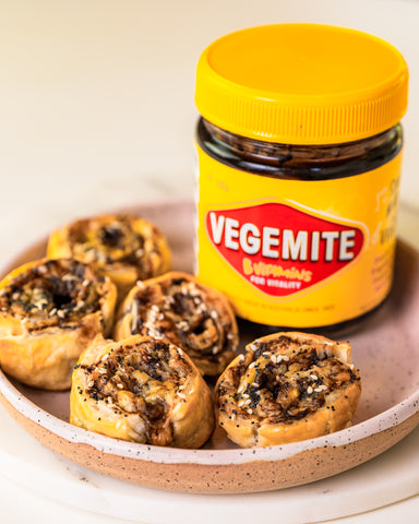 cheese and vegemite scrolls on a plate with a jar of vegemite