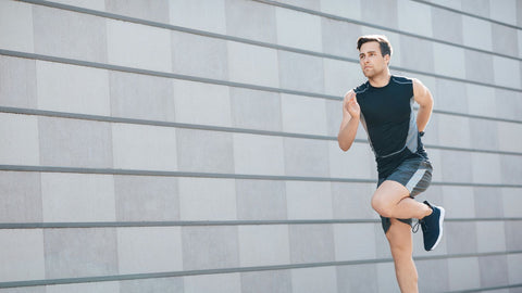 Cardio training in city. Young man in sportswear runs fast