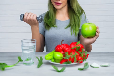 A woman holding a dumbbell and a fruit. Water and fruits on the table and a measuring tape that signifies diet