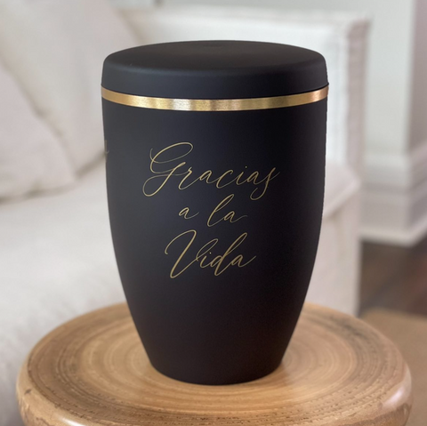 Black funeral urn with applied golden calligraphy 'Gracias a la vida'