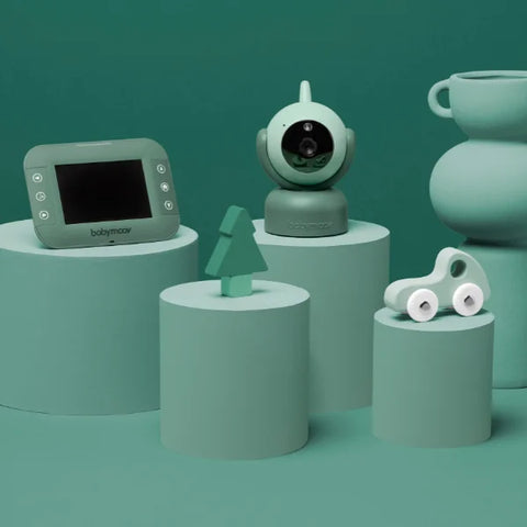 3d Render of the babymoov yoo master camera and monitor, in green colour. The product is set in a fun green room with other home accessories