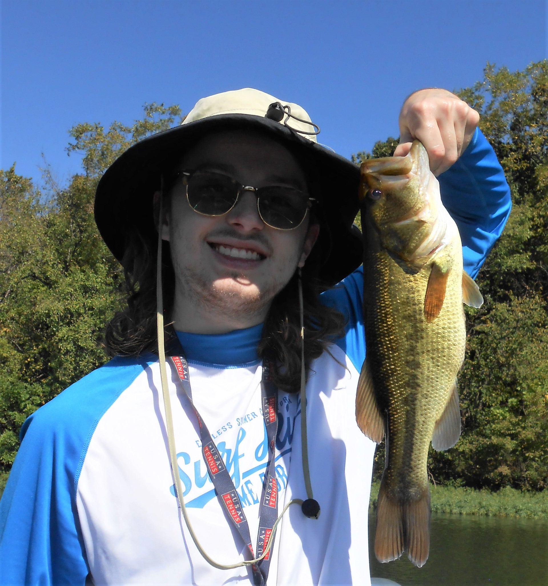 Young man with a small large mouth bass